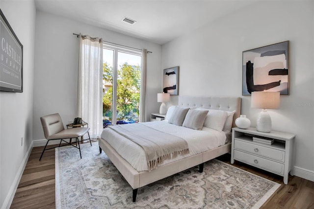 bedroom featuring wood finished floors, visible vents, and baseboards