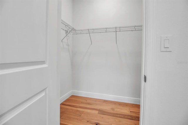 walk in closet with wood finished floors
