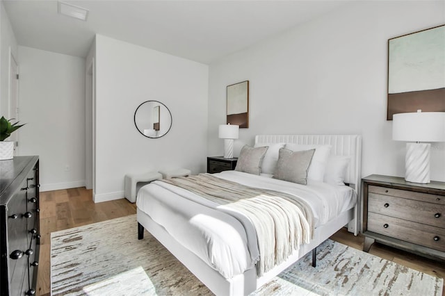 bedroom featuring baseboards, wood finished floors, and visible vents