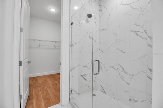 full bath with wood finished floors, a marble finish shower, a spacious closet, and recessed lighting