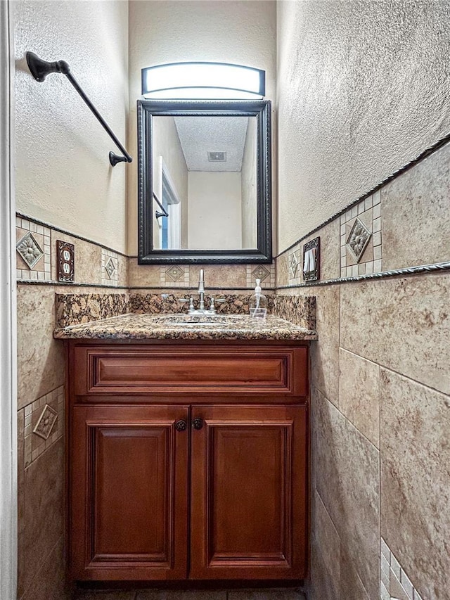 bathroom with vanity and tile walls