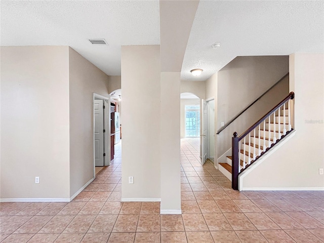 corridor with light tile patterned flooring and a textured ceiling