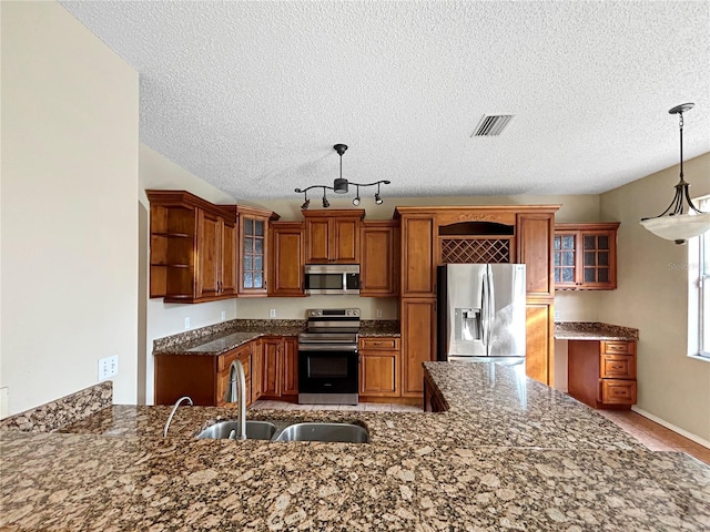 kitchen with kitchen peninsula, appliances with stainless steel finishes, hanging light fixtures, and sink