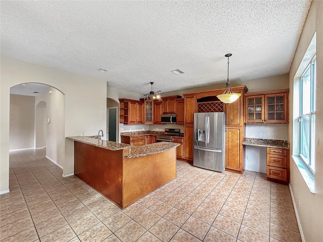 kitchen with pendant lighting, stone counters, light tile patterned flooring, kitchen peninsula, and stainless steel appliances