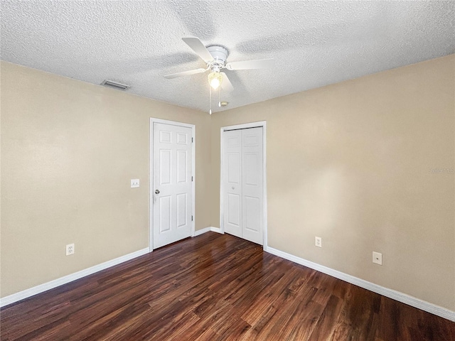 unfurnished bedroom with a closet, ceiling fan, dark hardwood / wood-style flooring, and a textured ceiling