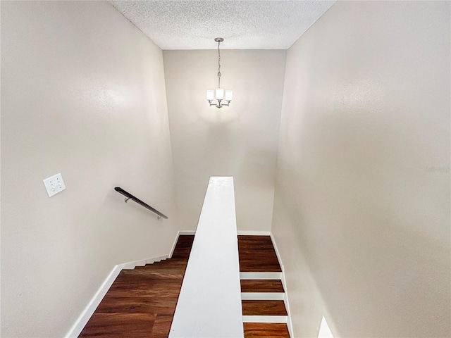 stairway with wood-type flooring and a textured ceiling