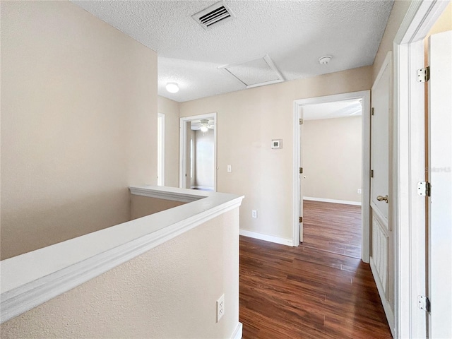 corridor featuring a textured ceiling and dark wood-type flooring