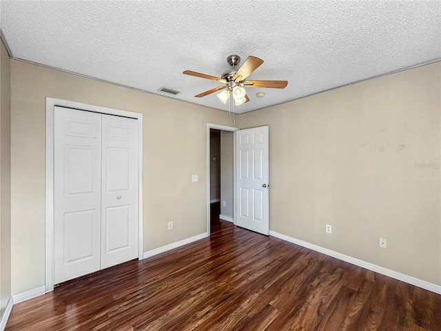 unfurnished bedroom featuring ceiling fan, a closet, dark wood-type flooring, and a textured ceiling