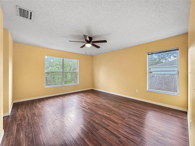 spare room featuring dark hardwood / wood-style floors, ceiling fan, and a textured ceiling