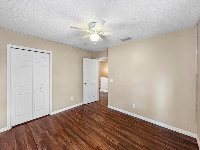 unfurnished bedroom with a textured ceiling, ceiling fan, a closet, and dark hardwood / wood-style floors