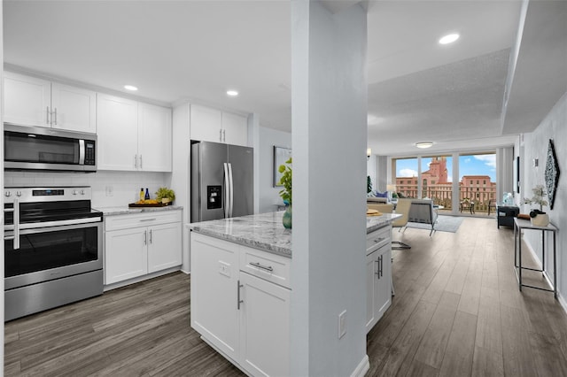 kitchen featuring dark hardwood / wood-style flooring, tasteful backsplash, light stone counters, stainless steel appliances, and white cabinets