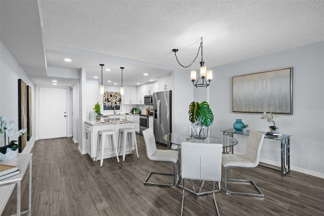 dining room with a textured ceiling, dark hardwood / wood-style floors, an inviting chandelier, and sink