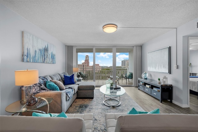 living room featuring floor to ceiling windows, light hardwood / wood-style flooring, and a textured ceiling