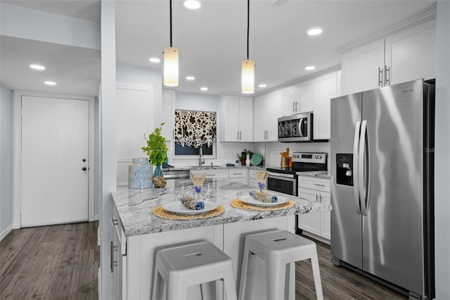 kitchen featuring hanging light fixtures, light stone counters, a kitchen bar, white cabinetry, and stainless steel appliances