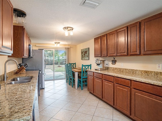 kitchen with light stone countertops, sink, light tile patterned floors, and a textured ceiling