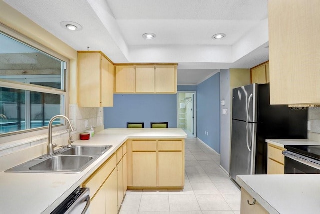 kitchen with kitchen peninsula, light brown cabinetry, decorative backsplash, dishwashing machine, and sink