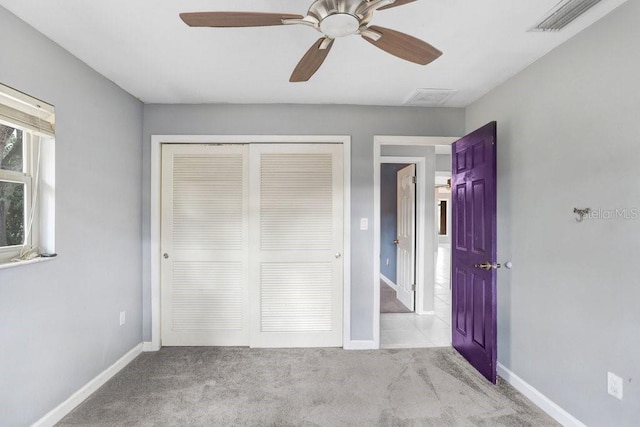 unfurnished bedroom featuring ceiling fan, light colored carpet, and a closet