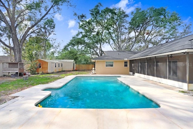 view of swimming pool featuring a sunroom, a patio area, and an outdoor structure