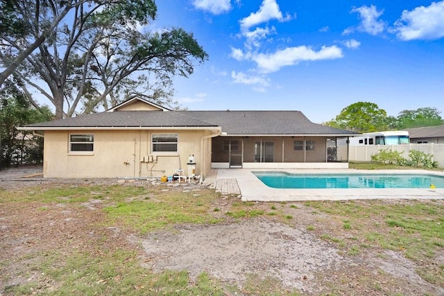 rear view of property with a fenced in pool, a patio area, and a sunroom