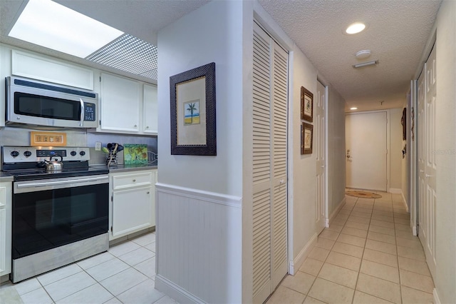 kitchen featuring white cabinets, a textured ceiling, stainless steel appliances, and light tile patterned flooring