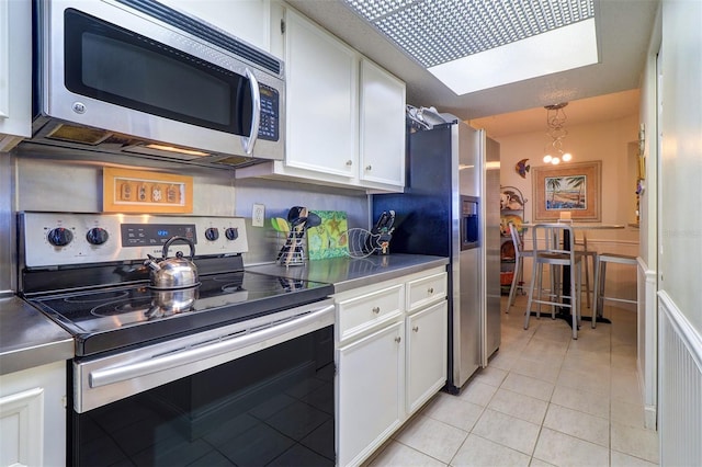 kitchen featuring white cabinets, a chandelier, light tile patterned floors, and appliances with stainless steel finishes