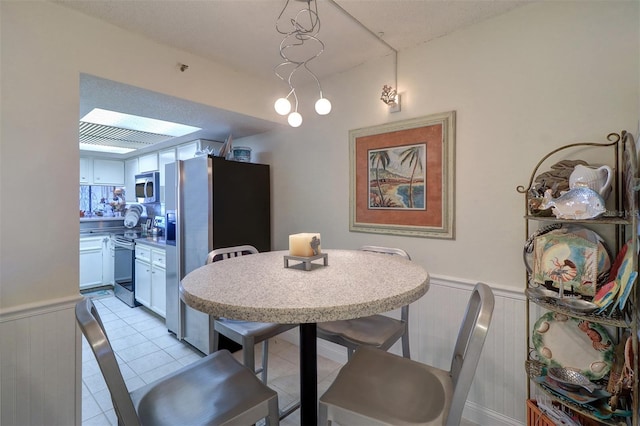 dining area with a skylight and light tile patterned flooring