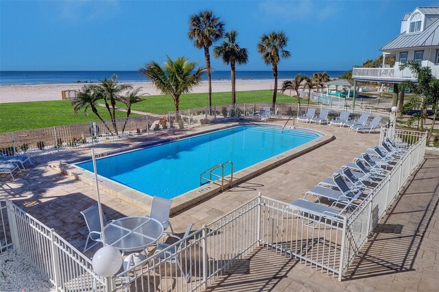 pool featuring a patio area, fence, and a water view