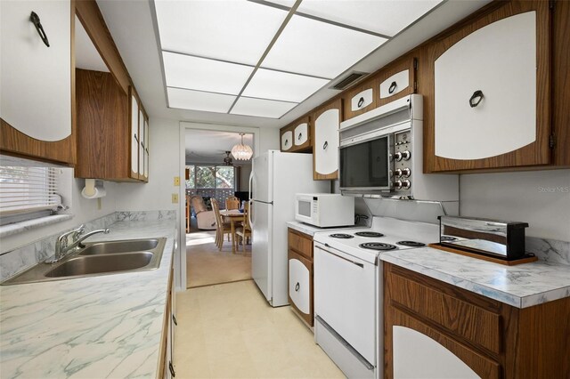 kitchen with a notable chandelier, white appliances, and sink