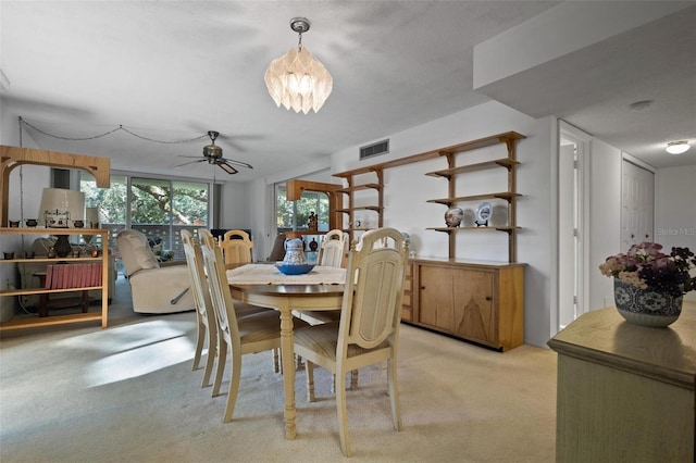 dining area featuring ceiling fan with notable chandelier and light colored carpet