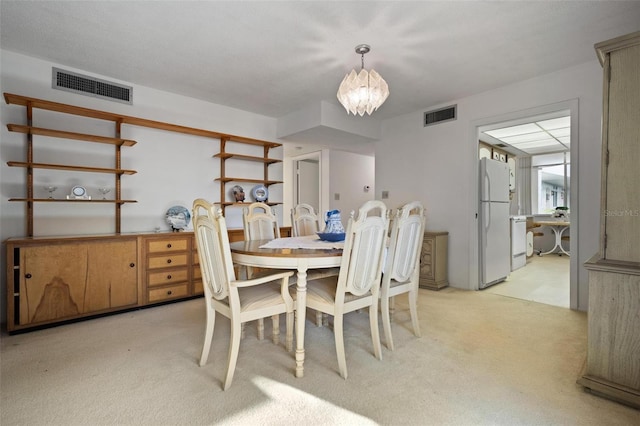 dining space featuring light carpet and an inviting chandelier