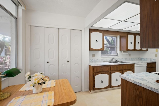 kitchen with white dishwasher, light countertops, a sink, and a textured ceiling
