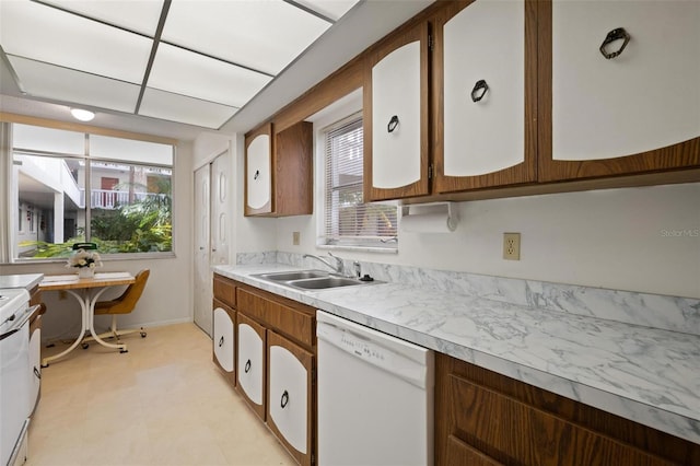 kitchen featuring light countertops, a sink, a wealth of natural light, and white appliances