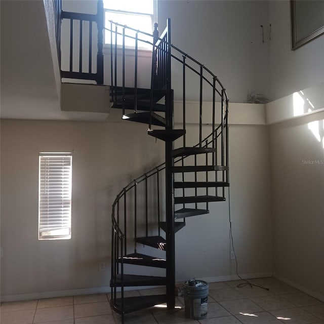 stairs with tile patterned flooring and a towering ceiling