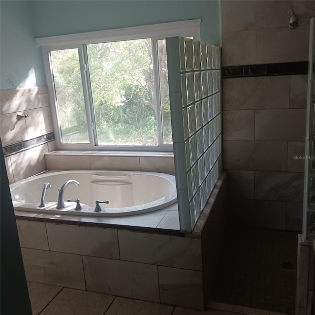 bathroom with tile patterned flooring, a healthy amount of sunlight, and tiled bath