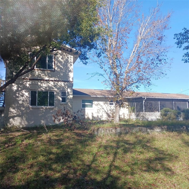 back of property featuring a lawn and a sunroom