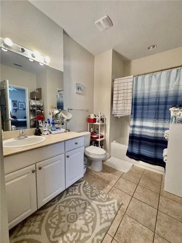 full bathroom featuring vanity, tile patterned flooring, toilet, a textured ceiling, and shower / tub combo