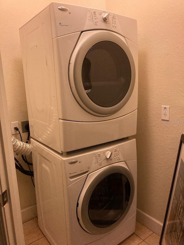 laundry room featuring stacked washer / dryer and light tile patterned flooring