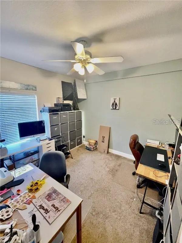 carpeted office space featuring ceiling fan