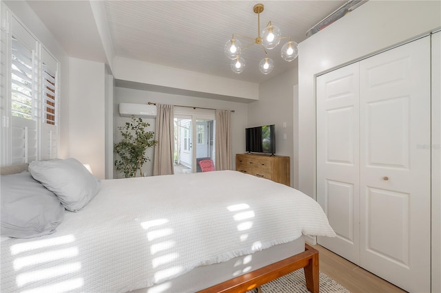 bedroom with a wall unit AC, a closet, an inviting chandelier, and light hardwood / wood-style floors