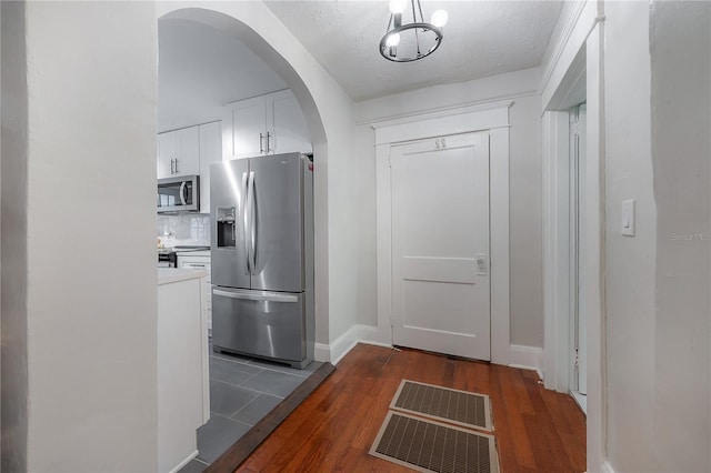 kitchen with stainless steel appliances, dark hardwood / wood-style flooring, white cabinetry, and a textured ceiling