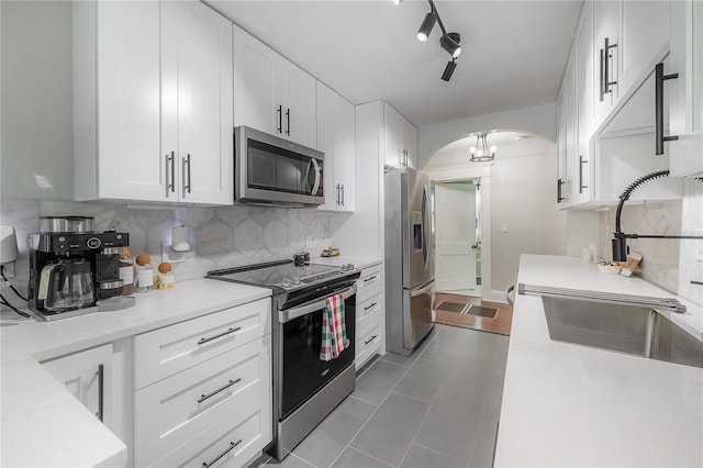 kitchen with appliances with stainless steel finishes, white cabinetry, and sink