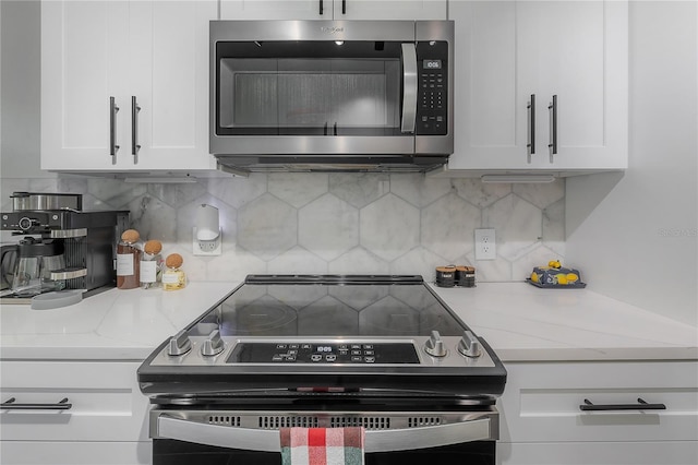 kitchen featuring appliances with stainless steel finishes, white cabinets, light stone countertops, and decorative backsplash