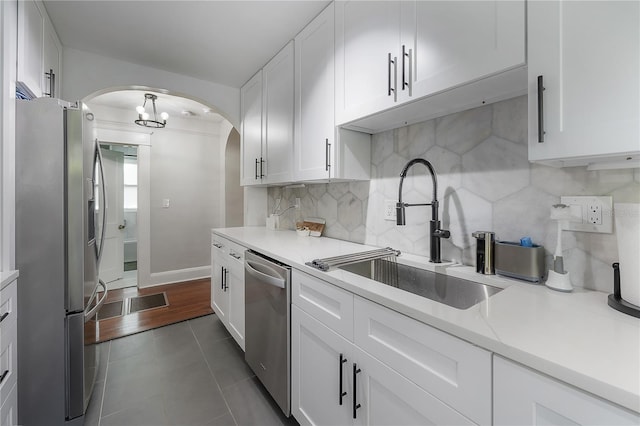 kitchen featuring stainless steel appliances, sink, white cabinetry, dark tile patterned flooring, and tasteful backsplash