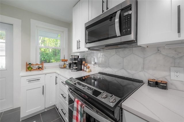 kitchen featuring stainless steel appliances, white cabinets, a healthy amount of sunlight, and dark tile patterned flooring