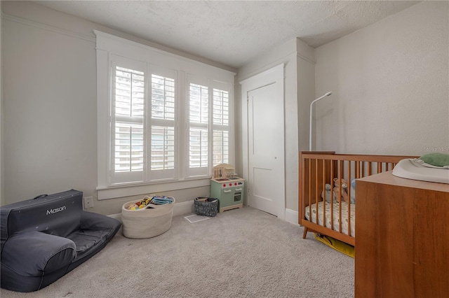 carpeted bedroom with a textured ceiling and a nursery area