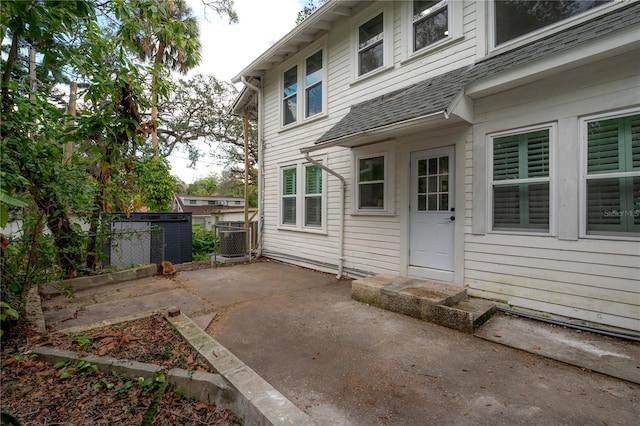 view of exterior entry with a patio and cooling unit