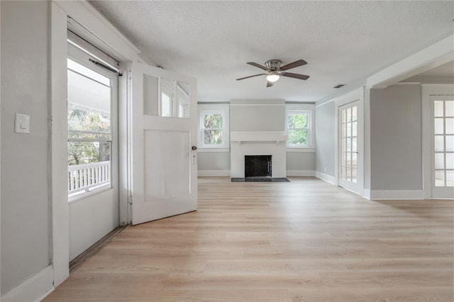 unfurnished living room featuring a textured ceiling, ceiling fan, and light hardwood / wood-style floors