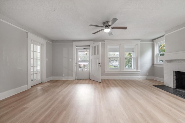 unfurnished living room featuring ceiling fan, a healthy amount of sunlight, a textured ceiling, and a fireplace