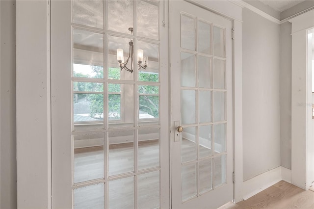 doorway featuring light wood-type flooring and a notable chandelier