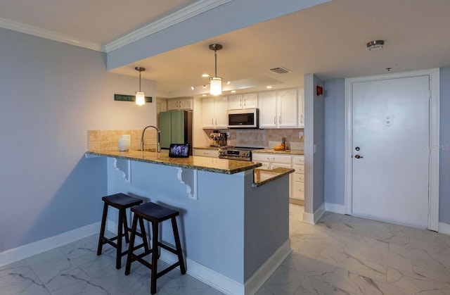 kitchen featuring white cabinetry, hanging light fixtures, kitchen peninsula, a breakfast bar, and appliances with stainless steel finishes